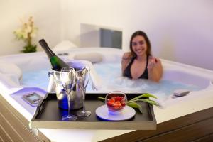 托尔博莱拉戈迪加尔达酒店的坐在浴缸里的女人,喝一瓶葡萄酒