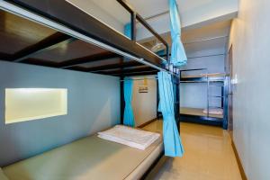曼谷瑞思提尼旅舍的客房内的双层床配有蓝色窗帘