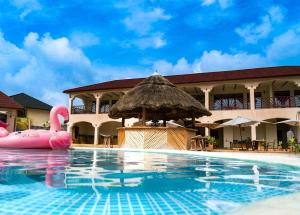 帕杰Paje Blu Boutique Hotel的一个带草伞和粉红色充气木筏的游泳池