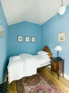 塞尔布里奇Castletown Gate House的蓝色的卧室配有一张床和一张带台灯的桌子