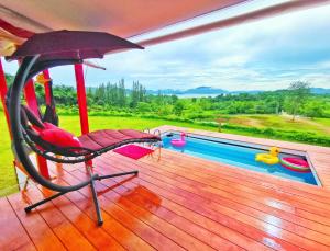 Ban Khao Dok Maiบ้านฟาร์มรักพูลวิลล่าวิวทะเลสาปแก่งกระจาน的一个带椅子和遮阳伞的甲板和一个游泳池