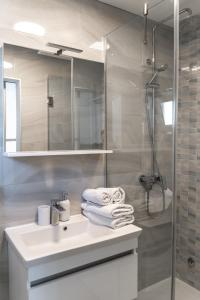 马卡尔斯卡Comfort Apartment Dorin的浴室配有盥洗盆、淋浴和毛巾