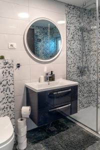 马卡尔斯卡Comfort Apartment Dorin的一间带水槽、镜子和淋浴的浴室