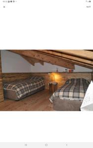 摩德纳迪-坎皮格里奥Mansarda la Baita的铺有木地板的客房内的两张床