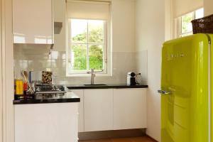 海滨诺德韦克海特埃尔斯特惠斯耶度假屋的厨房配有白色橱柜和绿色冰箱。