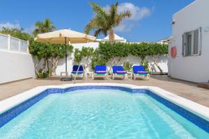 卡门港Villa hermosa的一个带椅子和遮阳伞的游泳池