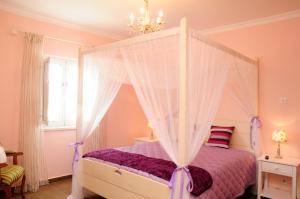 阿尔莫多瓦Corvos e Cadavais的一间卧室配有一张带紫色棉被的天蓬床