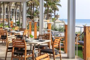 维洛海滩金普顿维罗海滩Spa酒店 的餐厅设有桌椅,以大海为背景