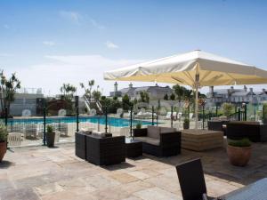 托基TLH Victoria Hotel - TLH Leisure, Entertainment and Spa Resort的一个带白色遮阳伞和椅子的庭院和一个游泳池