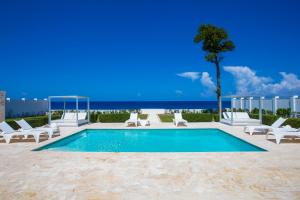 苏莎亚Ocean Village Deluxe Resort & Spa的一个带椅子和一棵树的游泳池以及大海