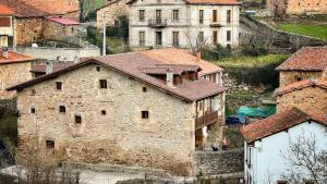 CiceraLa Valuisilla, hotel rural的一座古老的石头建筑,位于一座拥有房屋的村庄