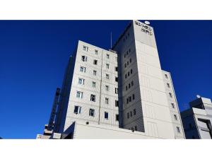 TorideCentral Hotel Toride - Vacation STAY 09920v的一座高大的白色建筑,后面有蓝色的天空