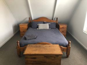 邓斯伯勒Dunsborough Beach Shack的一间卧室配有一张木床和木桌