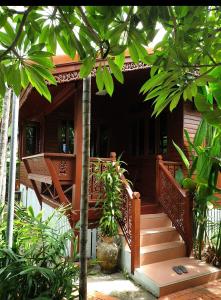 卡塔海滩Thai authentic wooden house at Kata的一座带木制楼梯的房屋,通往门廊