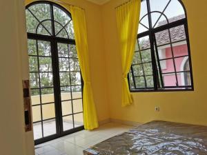 展玉Villa Kota Bunga 2 kamar full wifi harga budget的一间卧室设有2扇大窗户,墙壁为黄色