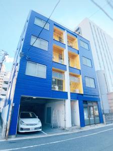 广岛OUCHI HOTEL Nagarekawa with Dogs的蓝色的建筑,前面有停车位