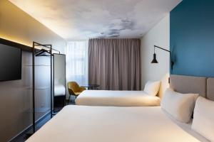 马赛Ibis Marseille Centre Prefecture的一间酒店客房,设有两张床和电视