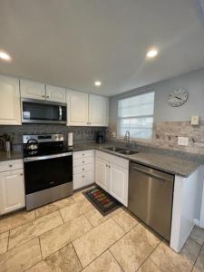 Point O'RocksIsland House Beach Resort 4的厨房配有白色橱柜和黑炉灶烤箱。