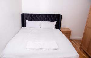 利兹Neptune Apartments的一间卧室配有一张白色的床和黑色床头板