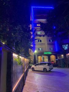 胡志明市Ha Long Hotel Thủ Đức HCMC的夜间停在大楼旁边的白色汽车