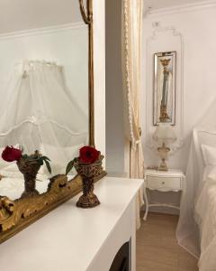 蒂米什瓦拉FSF Boutique Apartament的白色卧室配有镜子和玫瑰花在桌子上