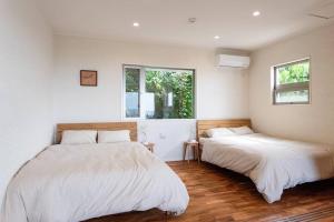 南城villa modama的配有白色墙壁和木地板的客房内的两张床