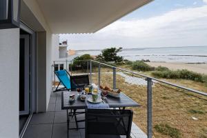 拉盖里尼耶尔Superbe appartement neuf face plage sur l ile de Noirmoutier的海滩景阳台桌子