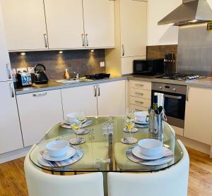 巴洛赫Riverside View Apartment in Balloch, Loch Lomond的厨房配有玻璃桌和酒杯