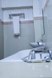 坎帕拉Steric Hotel Kampala的浴室水槽设有水龙头和镜子