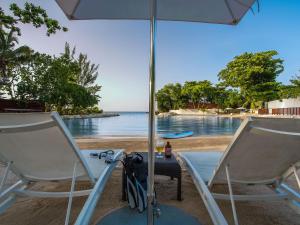 安东尼奥港三叉戟酒店 的海滩上的两把椅子和一把遮阳伞