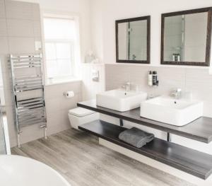 Coltishall诺福克米德酒店的白色的浴室设有2个盥洗盆和1个卫生间。
