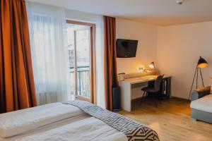 穆劳附近圣洛伦岑Hotel Alpenblick Kreischberg的配有一张床、一张书桌和一扇窗户的酒店客房