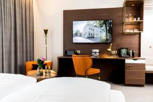 奥利希Hotel Am Schloss Aurich - Schlossresidenz的一间酒店客房,配有一张床和一台墙上的电视