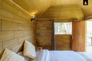西姆拉LivingStone Shimla Jungle Stay的一间卧室设有木墙、一张床和一个窗户
