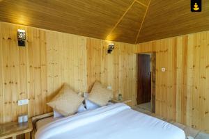 西姆拉LivingStone Shimla Jungle Stay的一间卧室设有木墙和一张带枕头的床。