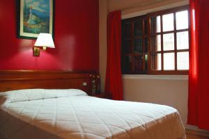 布宜诺斯艾利斯锦绣酒店的一间卧室设有一张红色墙壁和窗户的床