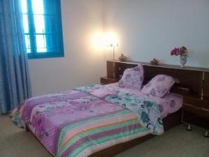 泰塔温Dar Essadeg的一间卧室配有一张带紫色毯子和枕头的床。