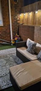 Pelton1 Grange Street的砖墙上设有一个带沙发和枕头的庭院