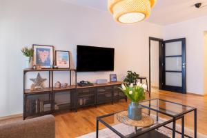 波雷奇City Garden Apartment的一间带电视和玻璃桌的客厅