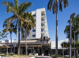 麦凯日吉尔斯麦凯套房酒店的一座高大的白色建筑,前面有棕榈树