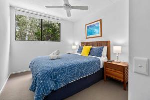 彩虹海滩Your place. Enjoy the beach retreat的一间卧室配有一张带蓝色棉被的床和窗户。