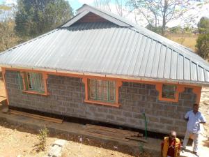 NyahururuSipili Village Residence的一座小砖房,前面有两个人