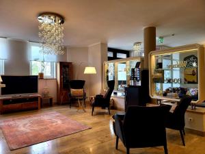 奥格斯堡Arthotel ANA Style Augsburg的客厅配有椅子、电视和吊灯。