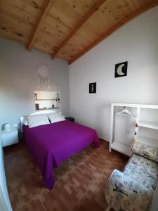 IsoraCASA LA LUNA的一间卧室配有一张紫色的床和一张沙发