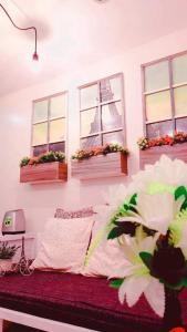 碧瑶French Nest at Baguio- Megatower Residences的一间卧室设有三扇窗户和一张鲜花床