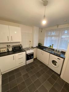 伦敦Lovely 3 Bedroom Apartment in the Heart of Hackney的厨房配有白色橱柜、洗衣机和水槽