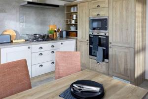 赛伦塞斯特Captivating Bluebell Lodge 2-bed Cotswolds caravan的厨房配有白色橱柜和桌椅
