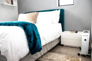 约翰内斯堡“Pop Inn” modern apartment in heart of Bryanston的一间卧室配有一张带蓝色毯子的床