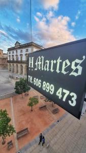 卡塞雷斯Hostal Martes Cáceres Plaza Mayor - Tercer piso SIN ascensor的建筑的标志,上面有时钟