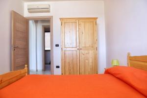 莱乌卡Appartamenti Marinelli - Santa Maria di Leuca的一间卧室配有橙色的床和木制衣柜